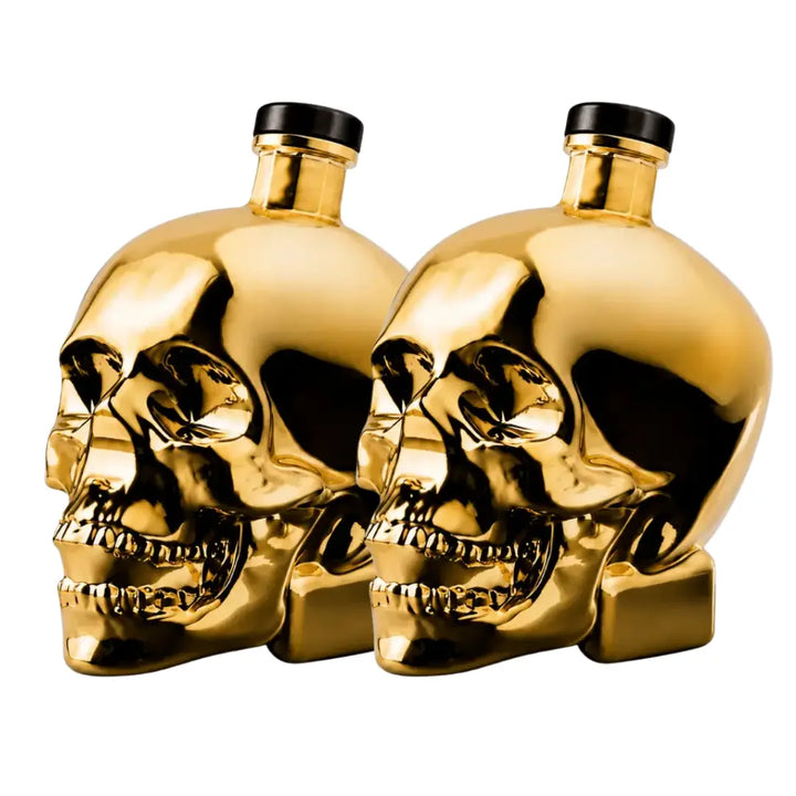 Two gleaming gold bottles shaped like human skulls with black caps, positioned side by side on a white background, highlight the bold design of Crystal Head Vodka Gold Edition (Pre-Order) by Crystal Head Vodka—a premium Canadian spirit celebrated for its unique style and outstanding quality.