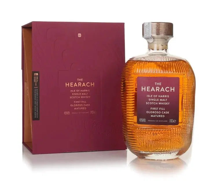 A bottle of The Hearach Isle of Harris Oloroso Cask Matured Single Malt Scotch Whisky 700mL stands by its maroon box, featuring textured glass, a copper top, and a maroon label that showcase the whisky’s distinctive island character.
