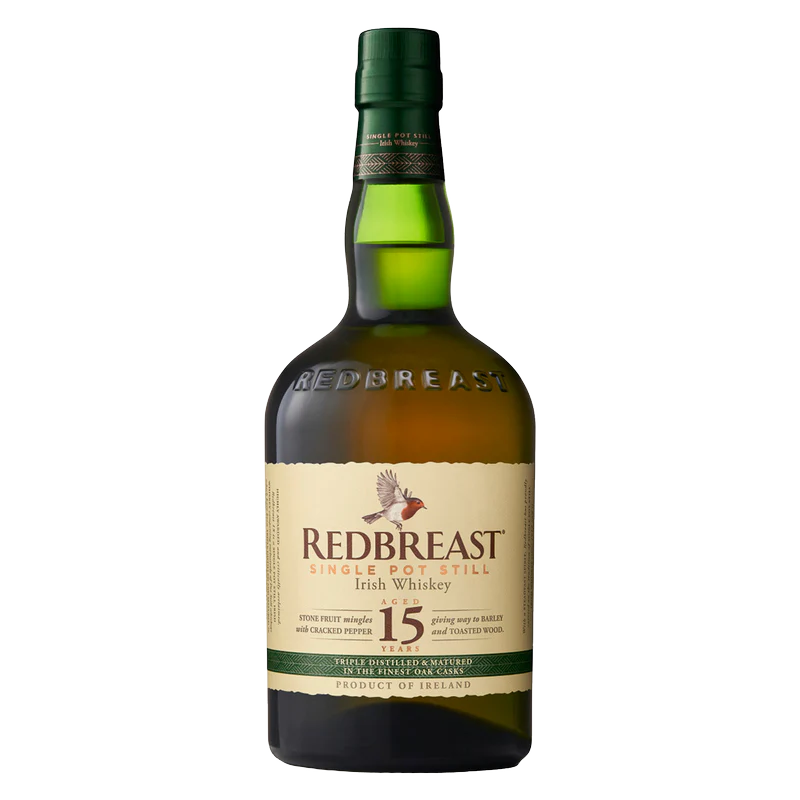 A bottle of Redbreast 15 Year Old Irish whiskey with a green glass body, cream label, and gold and red accents. The label displays a bird illustration and text highlighting this renowned Redbreast whiskey.