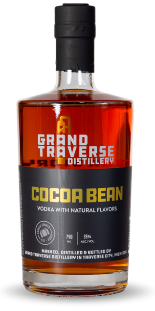 A bottle of Grand Traverse Distillery Cocoa Bean Vodka, with a black label in orange and white text, contains amber vodka at 35% alcohol and is crafted in Traverse City, Michigan.
