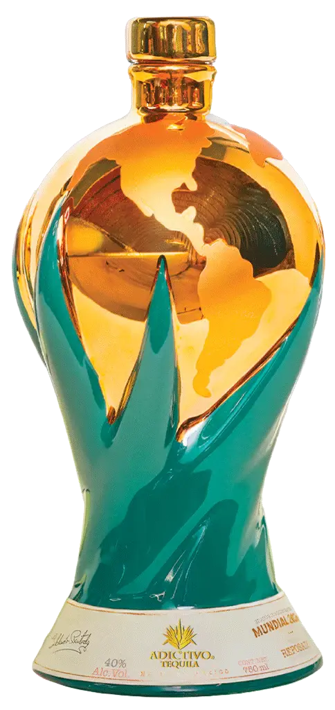 Tequila Adictivo's Doble Reposado 2026 World Cup Edition features a gold and green Earth-shaped bottle with the Americas highlighted and agave leaves at the base—an ideal collectible for World Cup celebrations.