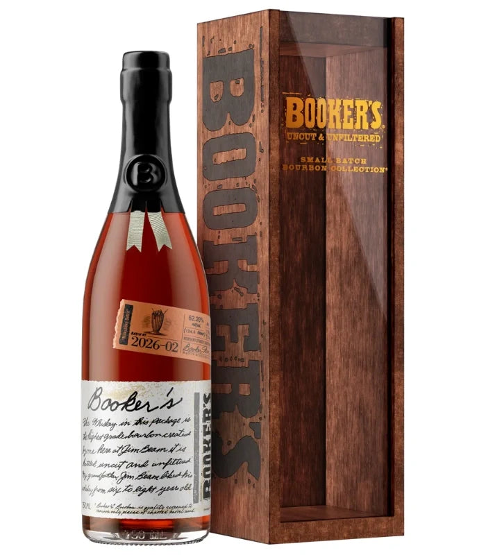 A bottle of Booker’s Batch 2026-02 “Milkshake Batch” Kentucky Straight Bourbon Whiskey by Booker’s, featuring its iconic wax seal and handwritten label, stands beside its wooden display box, which displays the BOOKER’S branding and product details along the side.
