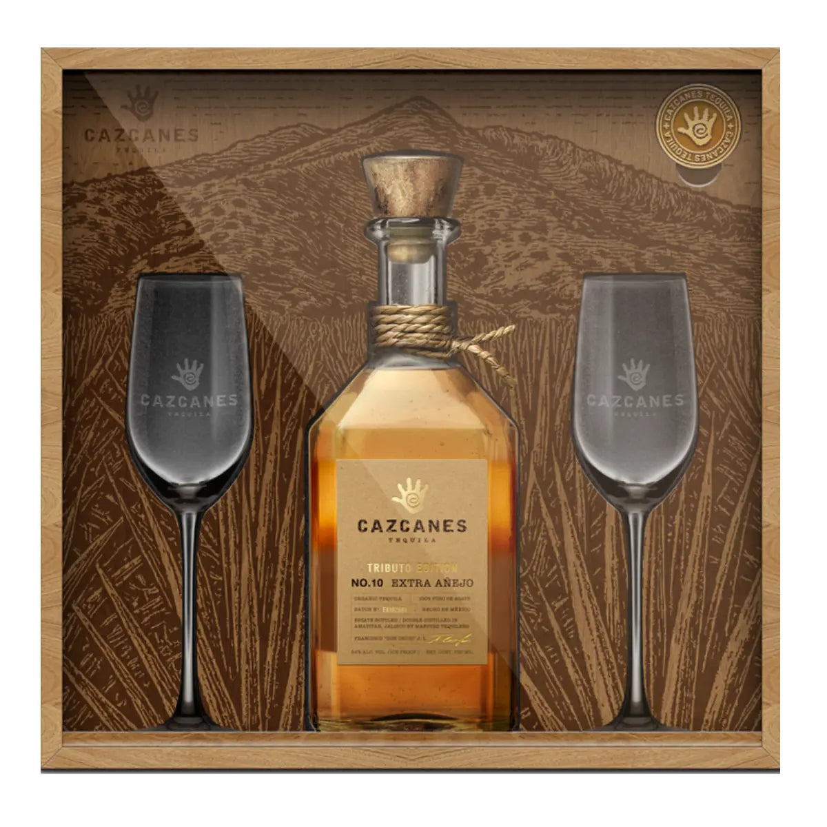 Gift box featuring Cazcanes No. 10 Extra Añejo Tributo Edition Tequila 750mL Gift Set with two black-stemmed glasses, a mountain backdrop, and a gold emblem in the top right corner.