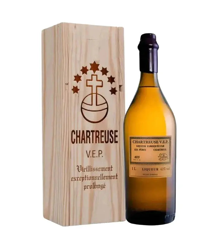 A bottle of Chartreuse Yellow V.E.P. Liqueur 1L by Chartreuse stands beside a wooden box featuring the Chartreuse logo—an ideal luxury gift for liqueur connoisseurs.
