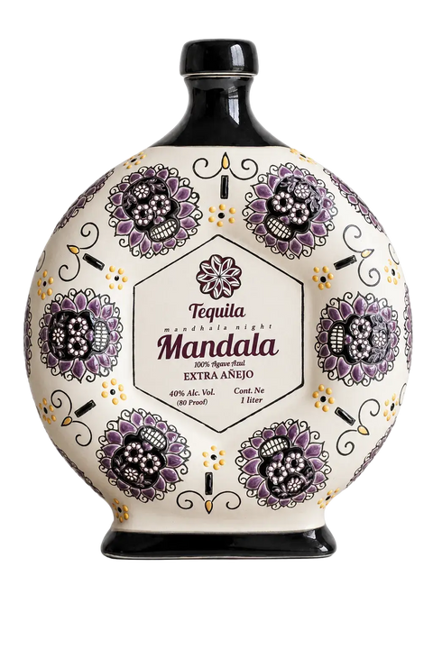 A round, decorative bottle of Tequila Mandala’s Extra Añejo Día de los Muertos “Guardians of Time” 2026 Limited Edition 1L (Pre-Order), adorned with purple floral patterns and black accents on a white background, featuring a central label with product details. This exclusive tequila is an elegant homage to artistry and tradition, making it perfect for collectors and enthusiasts alike.