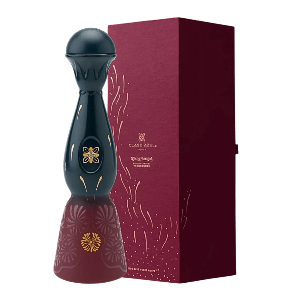 A tall, dark, decorative Clase Azul Día de Muertos Trascender 2026 Limited Edition Añejo Tequila 1L decanter with a rounded top and a flared base, featuring gold floral accents, standing next to a matching burgundy presentation box.