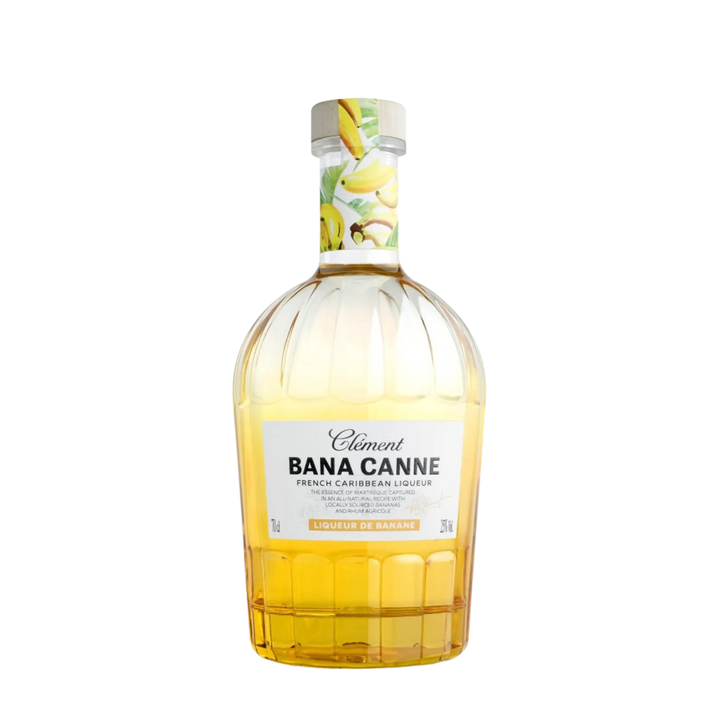 A clear glass bottle of Rhum Clément Bana Canne Liqueur by Rhum Clément features yellow-gold liquid, a decorated cap with bananas, and a label saying “BANA CANNE Liqueur de Banane.”.