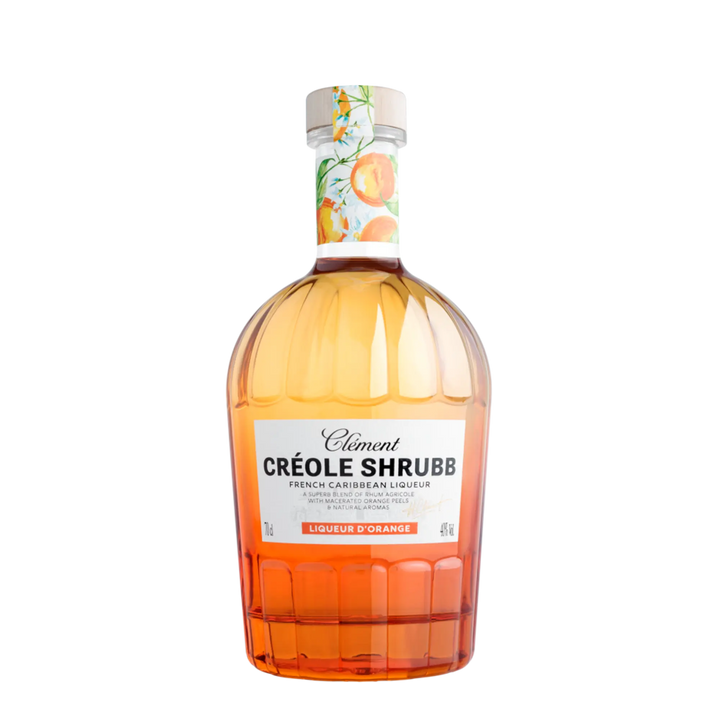 A bottle of Rhum Clément Créole Shrubb Orange Liqueur features a white label with orange accents, an illustrated fruit design on the neck, and is filled with vibrant amber-orange Caribbean rum liqueur from Rhum Clément.