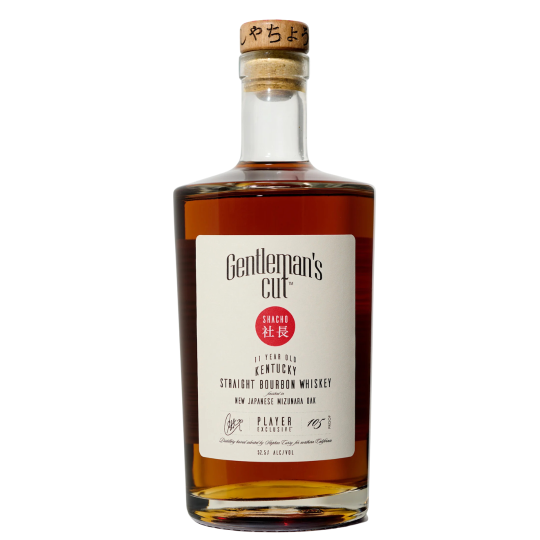 A bottle of Gentleman's Cut Player Exclusive Shacho Edition—Mizunara-finished bourbon with a cork stopper, white label, and red Japanese text—aged in Japanese Mizunara oak. A true collector's bourbon from Gentleman's Cut.