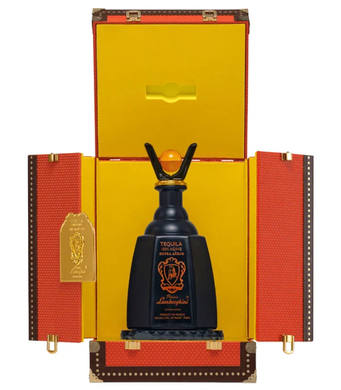 The Lamborghini Tequila Extra Anejo Gift Set by Lamborghini Wine & Spirits Collections features a black bottle with a gold-orange emblem, elegantly displayed upright in an open orange and yellow textured box with gold hardware—a true luxury tequila gift.