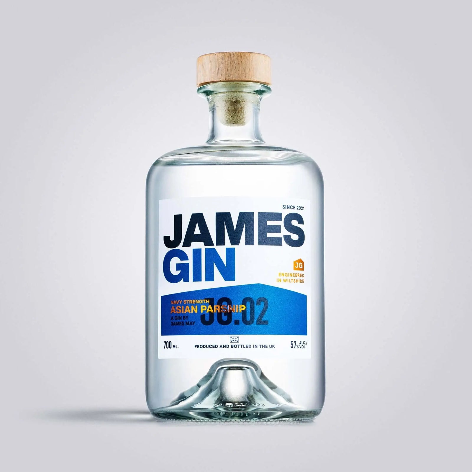 A clear James Gin Navy Strength 700mL 114 Proof bottle with a wooden cap and white label featuring blue and orange text is shown against a light gray backdrop, alongside a souvenir gift key chain.