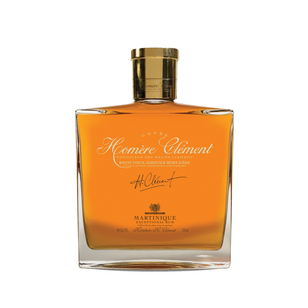 A square glass bottle of Rhum Clément Cuvée Homère features gold liquid, a gold cap, and elegant gold and white lettering on the label.