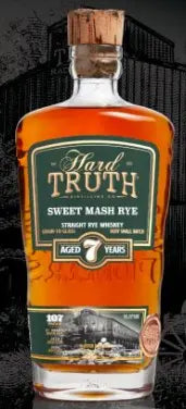 A bottle of Hard Truth 7 Year Sweet Mash Rye Whiskey features its amber liquid and a green and gold label showcasing age and proof, all set against a dark background.
