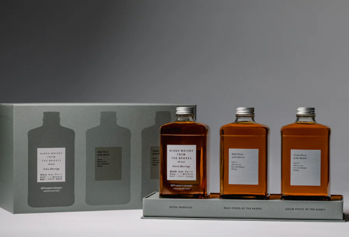 Three rectangular bottles from the Nikka From The Barrel Extra Marriage Gift Set are displayed before a gray gift box with bottle silhouettes and labeled sections, celebrating this limited edition release from Nikka.