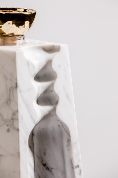 A close-up of a white marble object with sculpted grooves and a partial gold accent evokes the refined elegance of Volcan De Mi Tierra Coleccion I Hacienda La Gavilana Anejo Tequila, set against a neutral background.