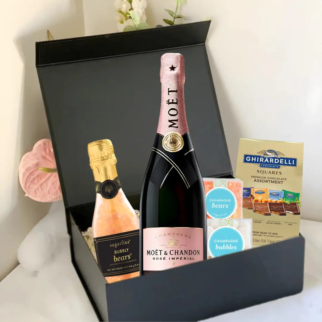 The Premium Champagne Gift Box by Main Street Liquor features a bottle of Moët &amp; Chandon Rosé, a mini sparkling wine, Ghirardelli chocolate squares, and champagne-flavored gummies in a luxurious black box on a white surface.