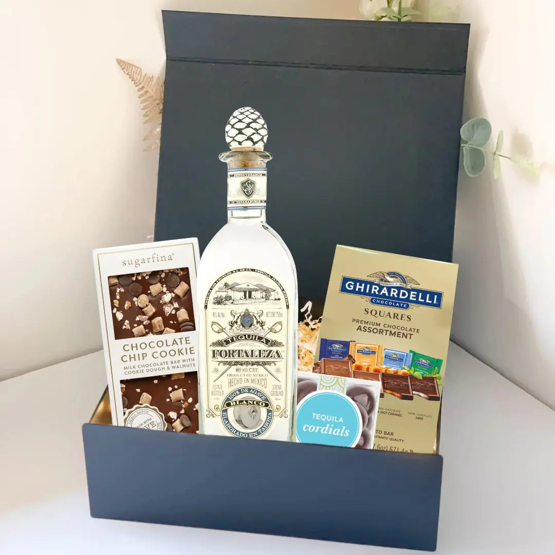 The Premium Tequila Gift Box from Main Street Liquor features Fortaleza tequila, Sugarfina chocolate chip cookie bites, and Ghirardelli chocolate squares, all beautifully arranged against a light background.