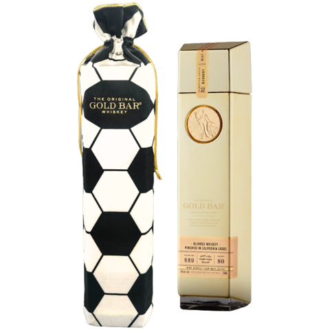 A bottle of Gold Bar Blended American Whiskey Soccer Bag Edition stands beside a black-and-white hexagon-patterned drawstring bag featuring the Gold Bar logo.