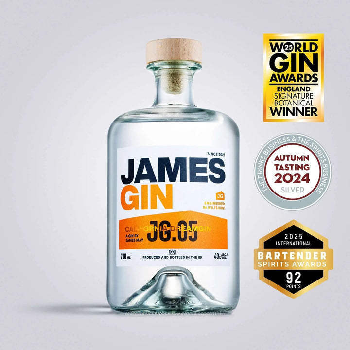 A clear glass bottle of James Gin California Dreamgin' with a wooden cap is centered, featuring orange and black text. Three award badges appear to the right, highlighting its gin competition accolades. Includes souvenir gift key chain.