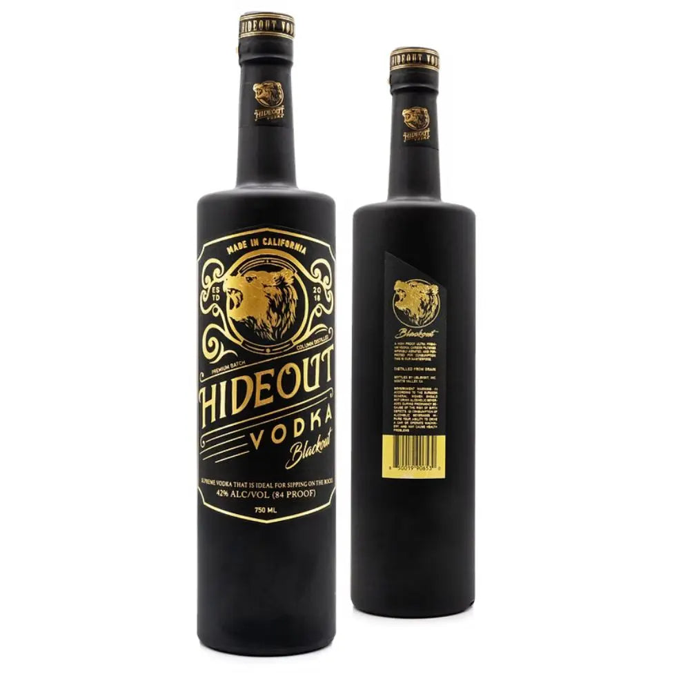 Two black bottles of Hideout Vodka Blackout Edition, one displaying the front label with a bear graphic and gold text, and the other showing the back label with product details and a barcode.