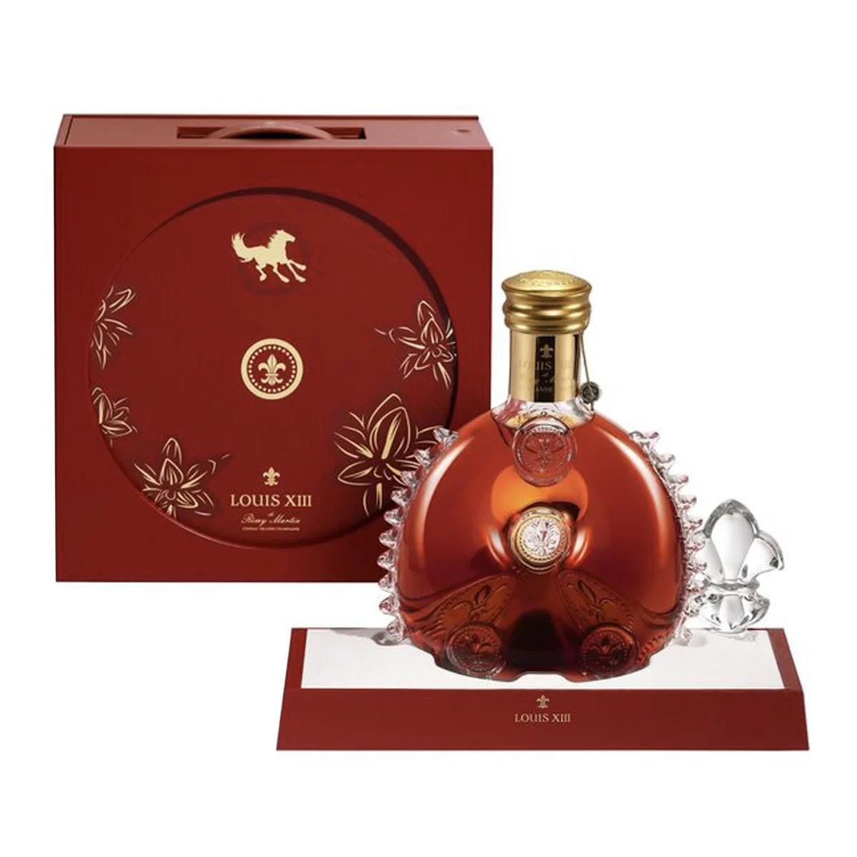 A LOUIS XIII 2026 Lunar New Year Limited Edition Cognac bottle with a gold cap stands before a festive collector’s box, featuring gold floral accents and Lunar New Year motifs. The bottle is partly enclosed in an intricate crystal decanter.