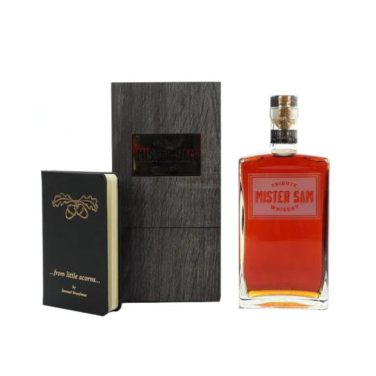 A bottle of Sazerac Mister Sam Tribute Whiskey Second Edition cask strength, presented in a dark wooden box with a black notebook featuring an acorn illustration and the phrase "...from little acorns..." on the cover.