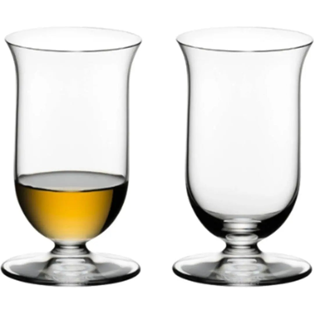 Two clear, footed glasses from the Riedel Vinum Single Malt Whisky Set of 2 by Riedel are displayed side by side on a white background; the left glass contains a small amount of amber liquid, while the right glass is empty. Expertly crafted from lead-free crystal, these elegant glasses are designed to elevate your single malt whisky tasting experience.