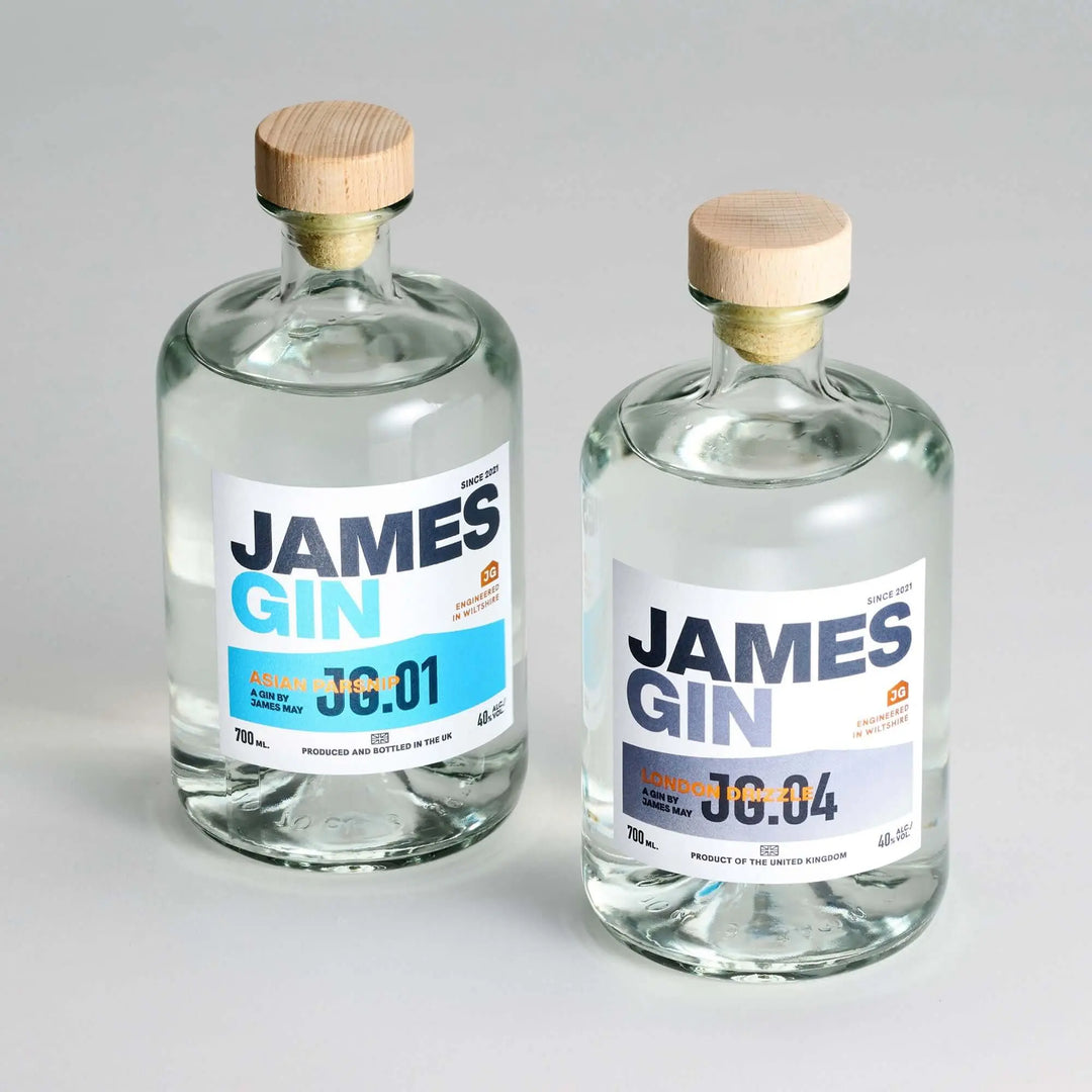 The James Gin US Starter Pack includes two clear glass bottles—Asian Parsnip 00:01 and London Dry 00:04—with wooden caps, white labels with blue and orange text, plus a souvenir gift key chain.